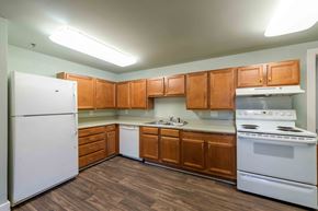 Kinston apartment for rent - A kitchen with white appliances and wooden cabinets.at Kinston Hotel Apartments, Kinston North Carolina