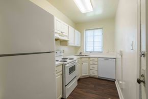 Kinston apartment for rent - A kitchen with white appliances and wooden floors.at Kinston Oaks Apartments, Kinston, NC