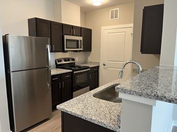 A kitchen with a granite counter top and stainless steel appliances.