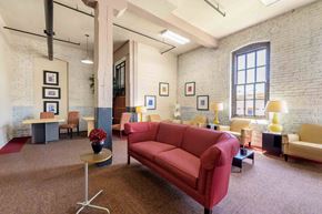 Kinston apartment for rent - A red couch is in the middle of a room with a carpet at Nantucket Lofts Apartments, Kinston, North Carolina