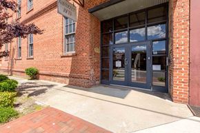 Kinston apartment for rent - The front of a brick building with a glass door and windows at Nantucket Lofts Apartments, North Carolina, 28501