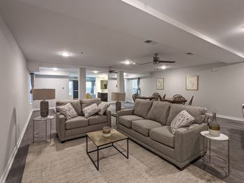 A living room with a grey couch and a glass coffee table.
