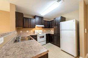 Rolesville apartment for rent - A kitchen with a white refrigerator and brown cabinets at The Grande at Granite Falls LLC Apartments, North Carolina