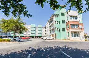 North Charlston apartment for rent - A street view of a multi-story building with cars parked in front.at West Yard Lofts, North Charlston, SC