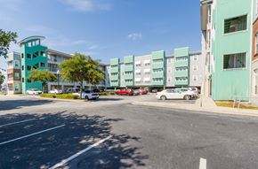 North Charlston apartment for rent - A parking lot with cars and a green building in the background.at West Yard Lofts, North Charlston South Carolina