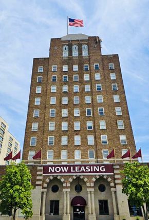 Kinston apartment for rent - A tall building with a sign that says "Now Leasing" in front of it.