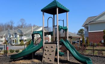 Playground with a green slide and a wooden structure.