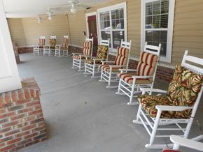 Concord apartment for rent - A row of white rocking chairs with red and green cushions are lined up on a porch.
