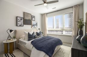 Parker apartment for rent - A bedroom with a bed, a nightstand, a lamp, a vase, and pictures on the wall.