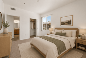 Goodyear apartment for rent - A bedroom with a large bed and a view of a house through the window.