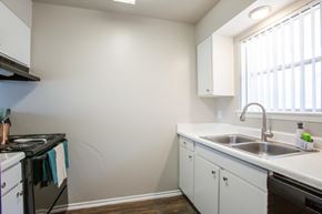 San Antonio apartment for rent - A kitchen with white cabinets and a black stove top oven.