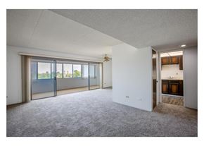 Tucson apartment for rent - A spacious room with grey carpet and a large window with sliding doors.