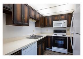 Tucson apartment for rent - A kitchen with brown cabinets and white appliances.