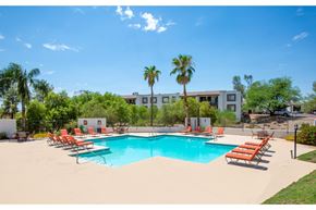 Tucson apartment for rent - A pool with chairs and a building in the background.