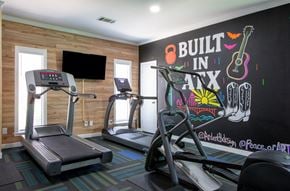 Austin apartment for rent - A gym with treadmills and a chalkboard wall that says "Built in Nate".