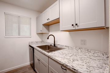 Tucson apartment for rent - A kitchen with white cabinets and a marble countertop.