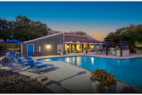 San Antonio apartment for rent - A poolside lounge area with chairs and a building in the background.