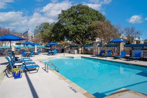 San Antonio apartment for rent - A pool surrounded by blue chairs and umbrellas.