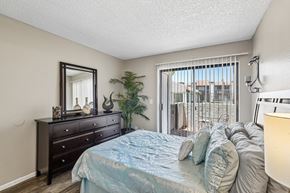 Glendale apartment for rent - A bedroom with a bed, dresser, mirror, and a plant.