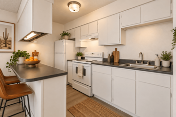 Tucson apartment for rent - A kitchen with white cabinets and a black countertop.