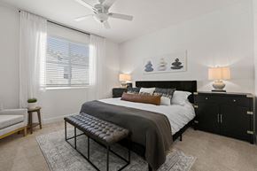 Phoenix townhouse for rent - A bedroom with a large bed, a bench, and a ceiling fan.