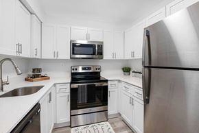 Pompano Beach apartment for rent - A modern kitchen with white cabinets and stainless steel appliances.