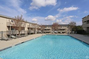 Columbia apartment for rent - A large swimming pool in front of a building with trees and a blue sky.