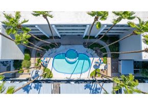 Tucson apartment for rent - A swimming pool surrounded by trees and a white wall.