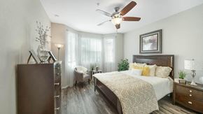 Tampa apartment for rent - A bedroom with a bed, dresser, and ceiling fan.