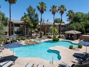 Goodyear apartment for rent - A swimming pool surrounded by palm trees and lounge chairs.
