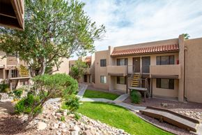 Tucson apartment for rent - A building with a red tile roof and a tree in front of it.
