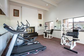 Tucson apartment for rent - A home gym with a treadmill, weights, and exercise machines.