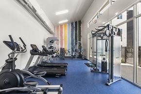Mesa apartment for rent - a gym with cardio machines and weights on a blue floor at SECOND AVE COMMONS | BRAND-NEW, Arizona