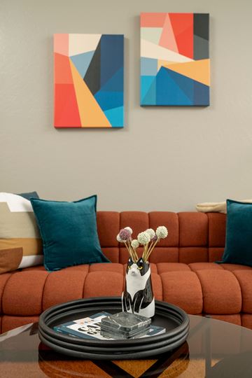 Tempe apartment for rent - A living room with a red couch and two abstract paintings on the wall.