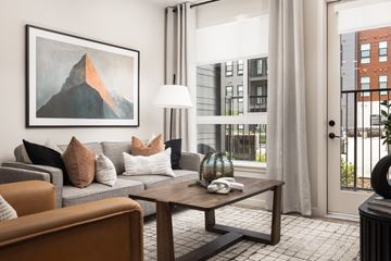 Lone Tree apartment for rent - A living room with a grey couch, a brown armchair, a wooden coffee table, and a painting on the wall.