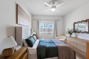Ft. Myers apartment for rent - A bedroom with a bed, a nightstand with a lamp, and a window with curtains.