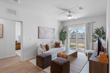 Ft. Myers apartment for rent - A living room with a white couch, a brown ottoman, and a painting on the wall.