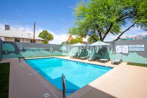 Tucson apartment for rent - A pool with a blue water and sun loungers and a mural