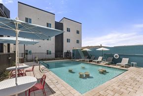 Mesa apartment for rent - a swimming pool with chairs and umbrellas and a building in the background at SECOND AVE COMMONS | BRAND-NEW, Mesa, Arizona