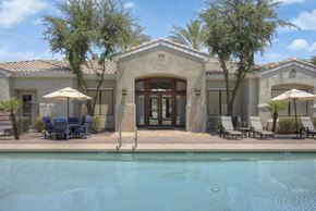 Gilbert apartment for rent - A pool in front of a house with a patio and chairs.