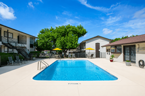 San Antonio apartment for rent - A swimming pool surrounded by a patio with chairs and umbrellas.