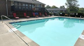 Lexington apartment for rent - A swimming pool with red chairs and a building in the background.