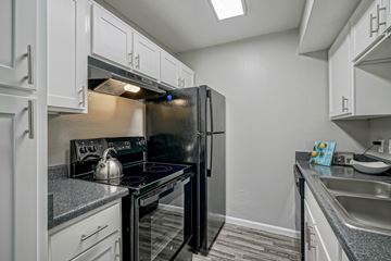 Albuquerque apartment for rent - A black refrigerator is in a kitchen with white cabinets.