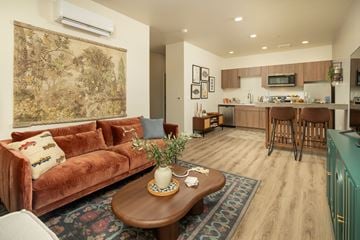 Peoria apartment for rent - A living room with a brown couch and a coffee table with a vase on it.