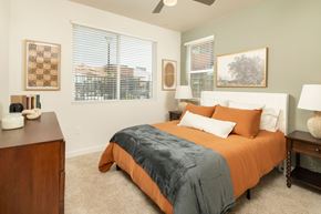 Peoria apartment for rent - A bedroom with a bed, nightstand, and window.