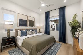 Queen Creek apartment for rent - A bedroom with a large bed and a window with blue curtains.