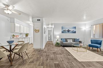 Tucson apartment for rent - A living room with a grey couch, a blue armchair, a glass table and a wooden floor.