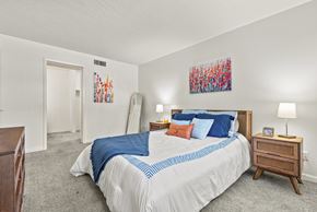 Tucson apartment for rent - A bedroom with a bed, nightstand, and two paintings on the wall.