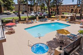 Tucson apartment for rent - A large swimming pool with a hot tub in the middle of a patio area.