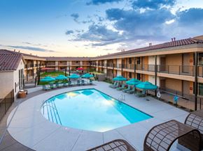 Tucson apartment for rent - A large outdoor swimming pool surrounded by lounge chairs and umbrellas.
